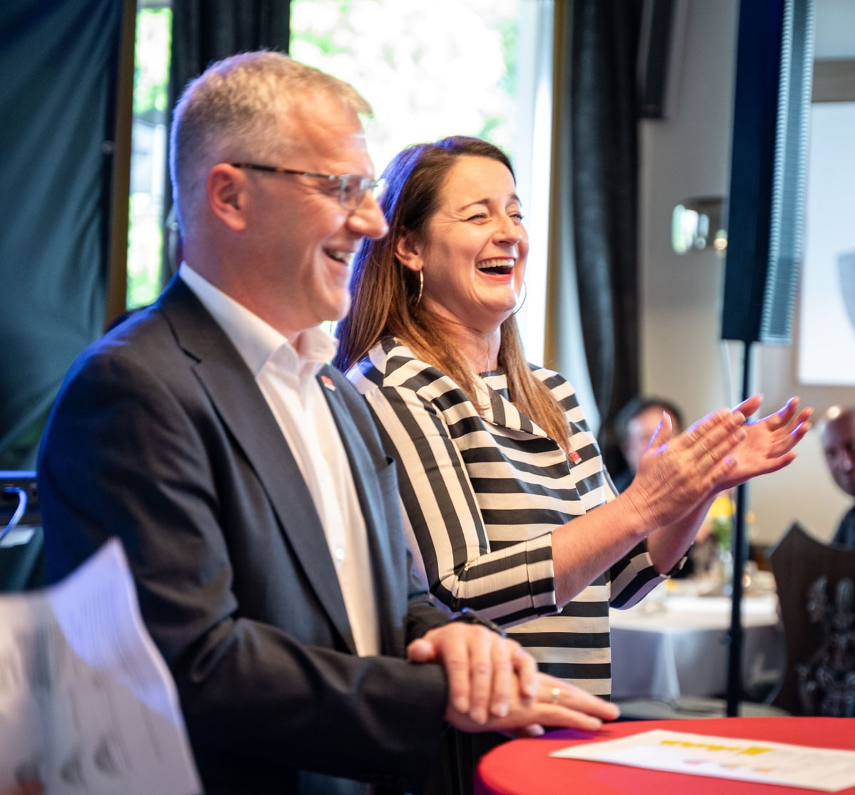 Geschäftsführung klatschend und lachend auf der Bühne